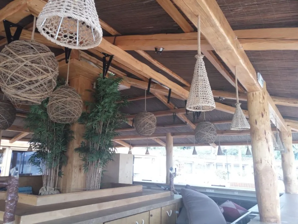 Ξύλινη πέργκολα με κρεμαστά φωτιστικά σε beach bar
