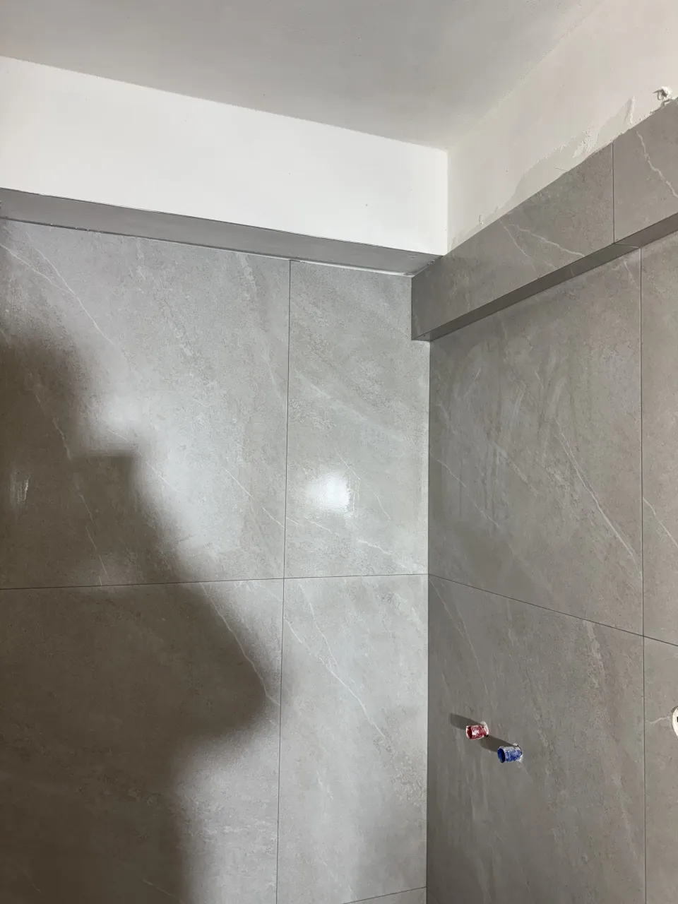 Τοίχος μπάνιου με γκρι πλακάκια μεγάλων διαστάσεων κατά την τοποθέτηση
